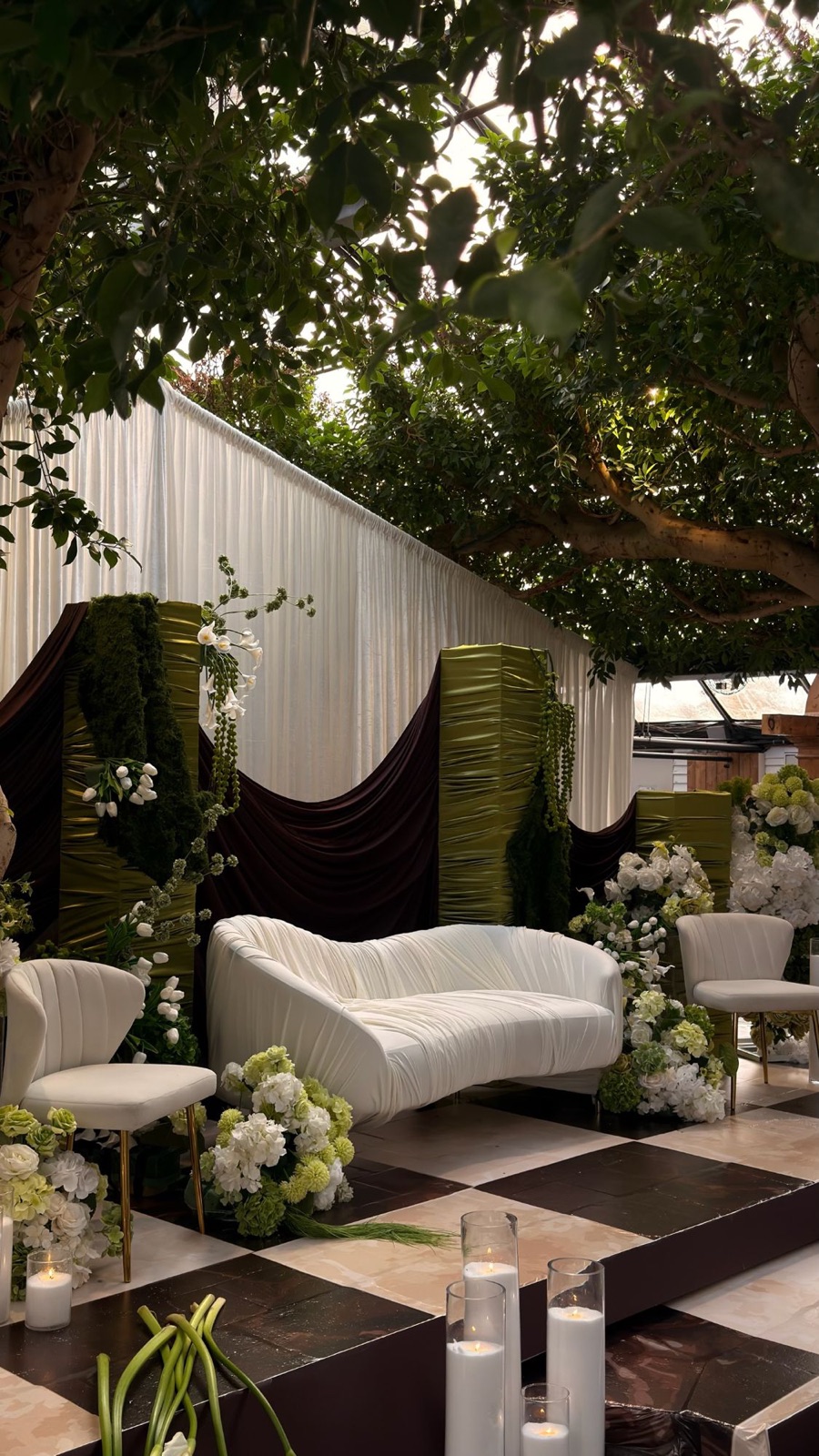 Garden stage with olive satin pillars, chocolate draping and white florals